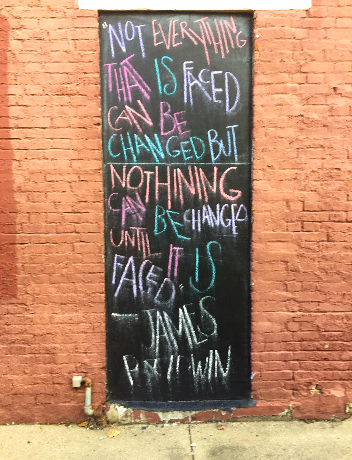 photo of chalked quote by James Baldwin on a panel. 